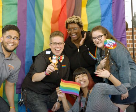 five students in front of rainbow flag