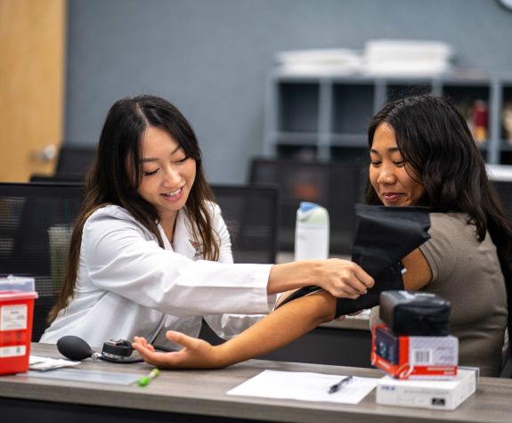 Health Ed. student taking the blood pressure of another health ed. student.