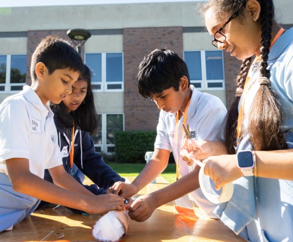 students work together to build a paper football on a folding table outside