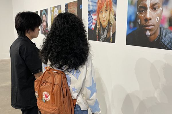 Two visitors look at wall of photos