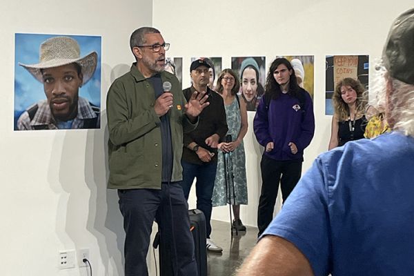 An artist talks to visitors about photo show