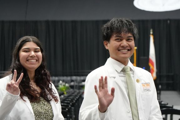 Two PharmD students waving and smiling at the camera