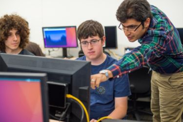 Professor working with students on computer 