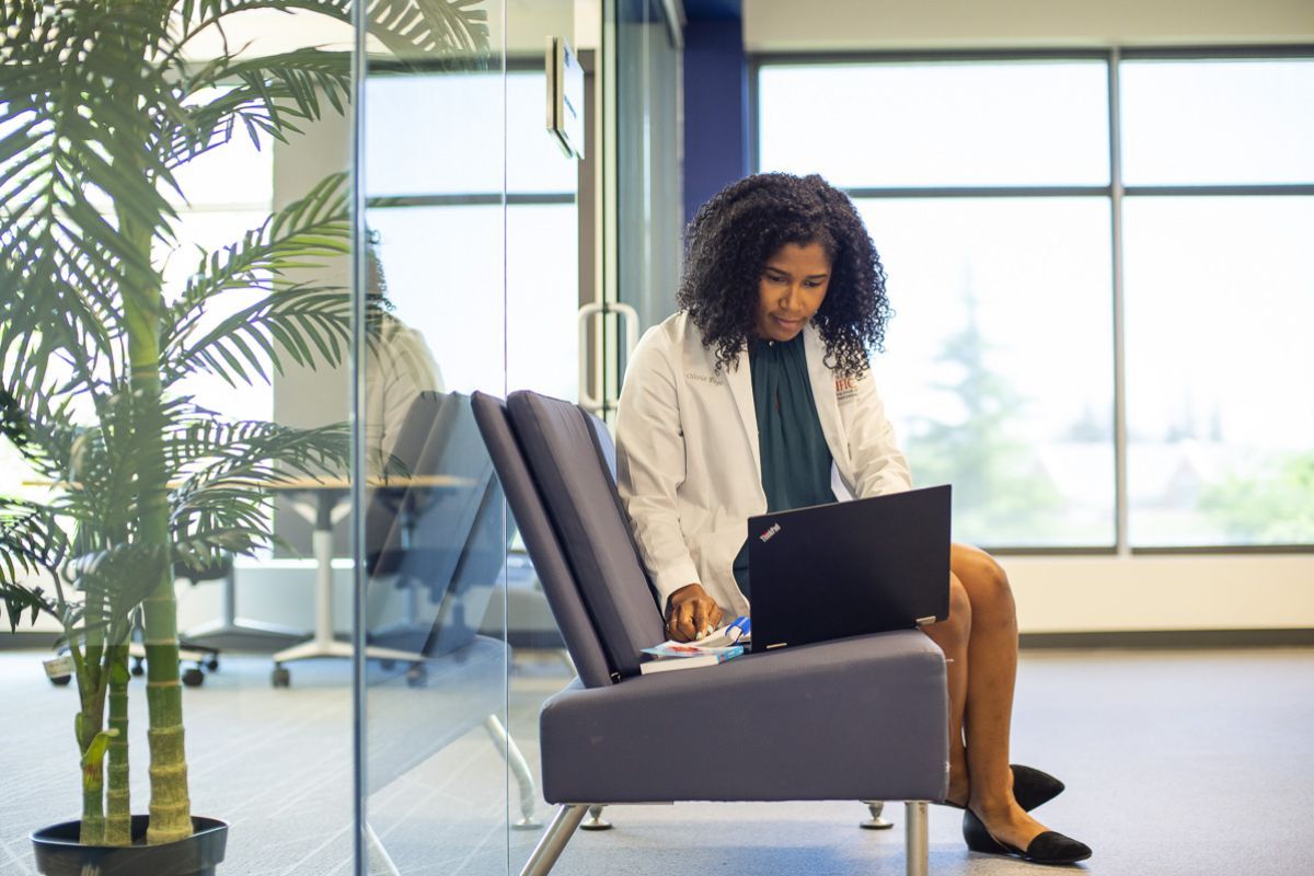 Woman typing on laptop, sitting in a chair