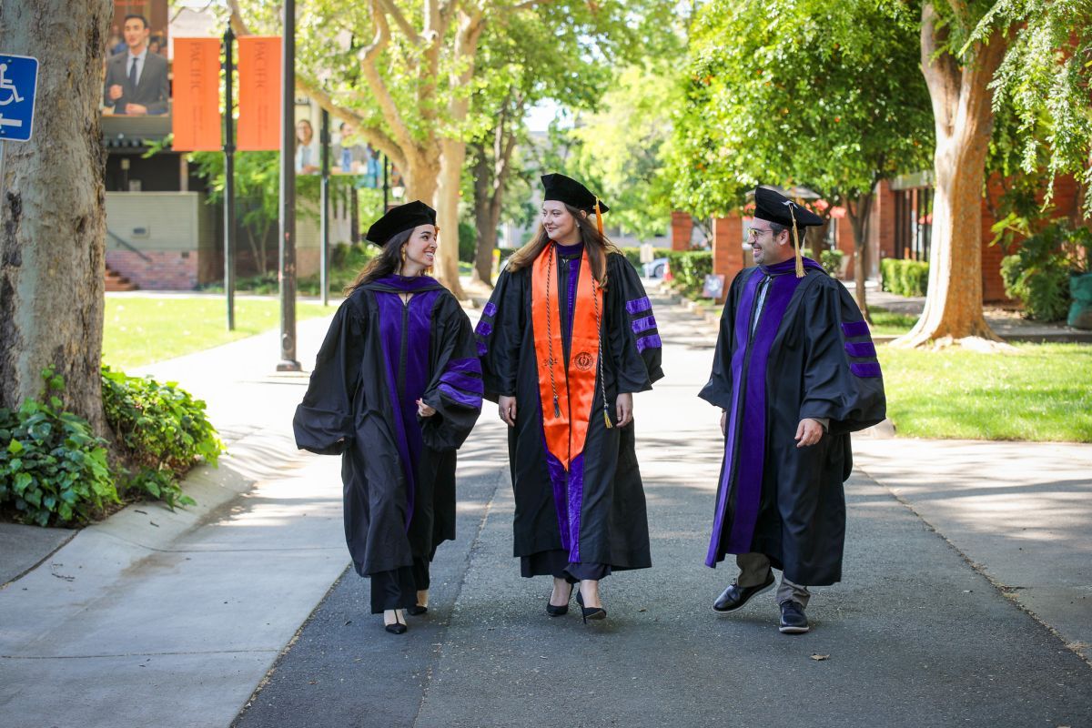 Three graduates walking on campus.