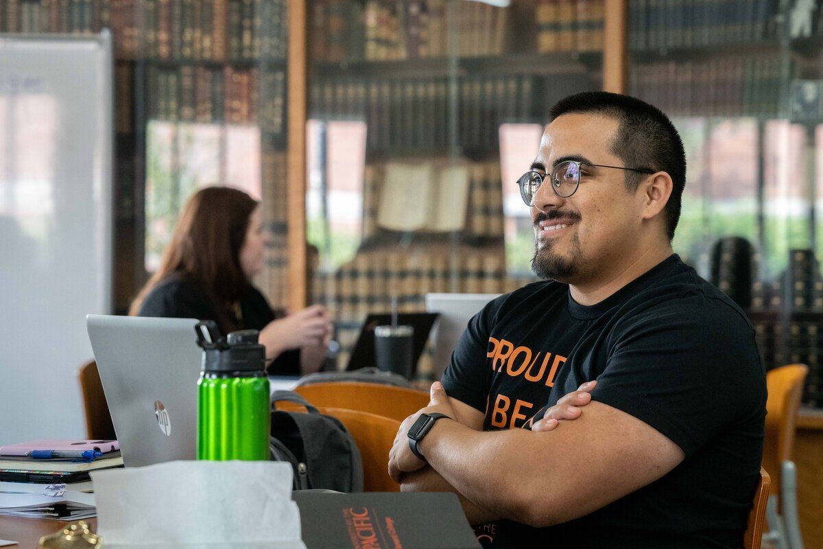 a student at a table with old books in the background
