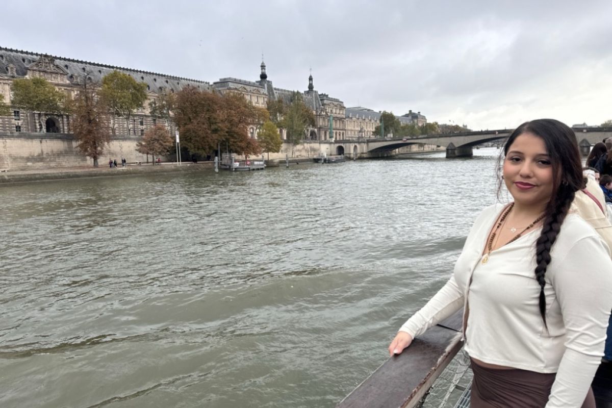 A student stands in front of the Seine River in Paris