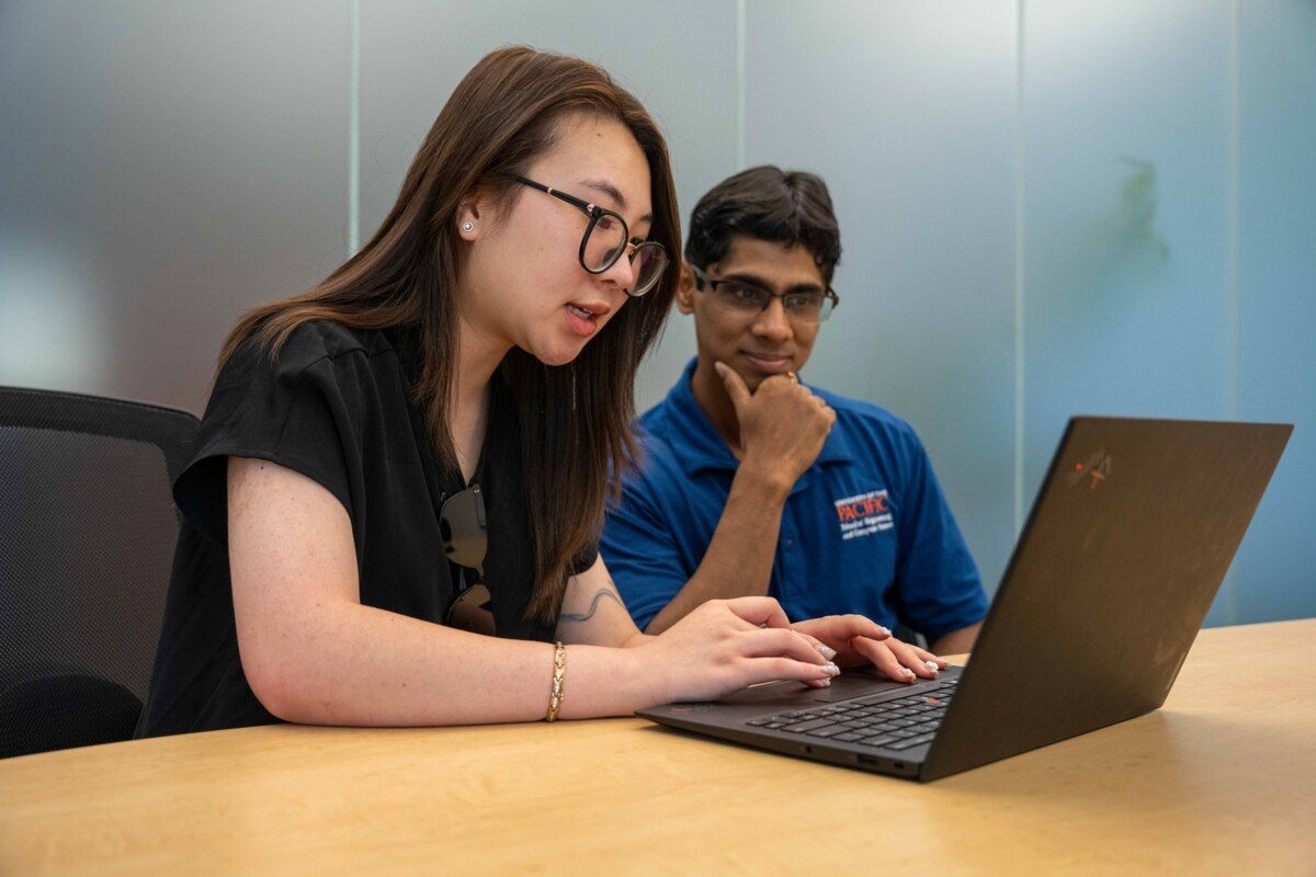 a student and a professor working together at a conference table