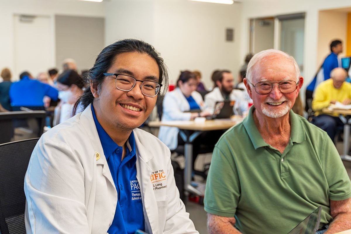 A pharmacy student and health care patient smiling at the camera