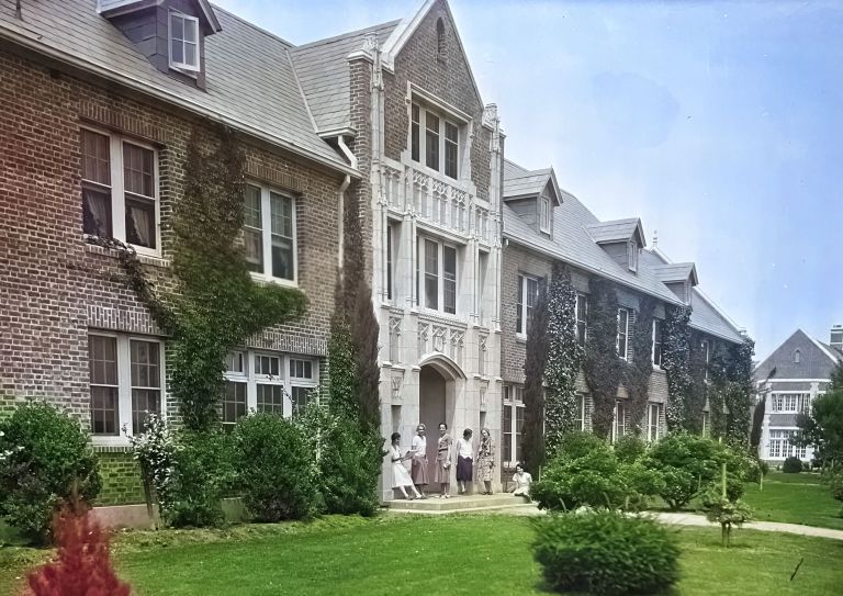A colorized photo of Southwest Hall with some women standing by its door