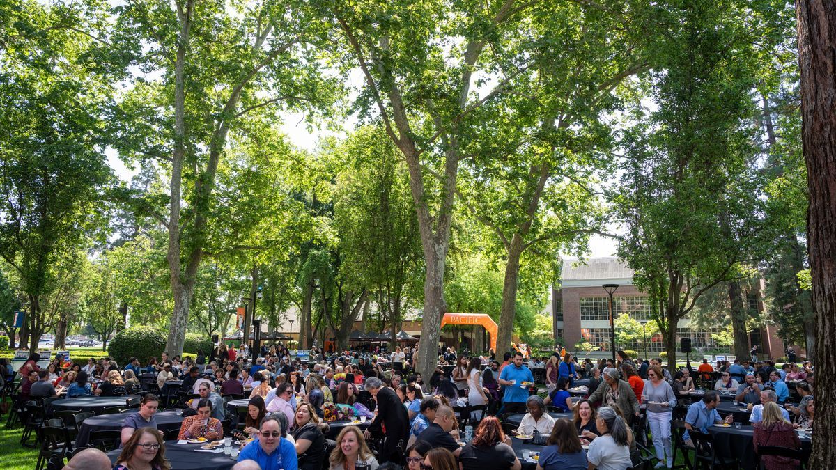 Staff and faculty sit at tables during a luncheon held outside on University of the Pacific's Stockton Campus.