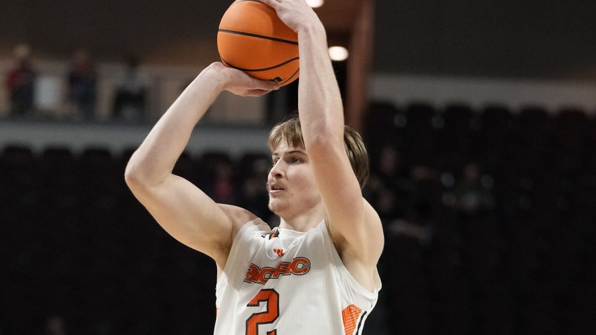 A basketball player holds the ball over his head as he prepares to shoot a basket.