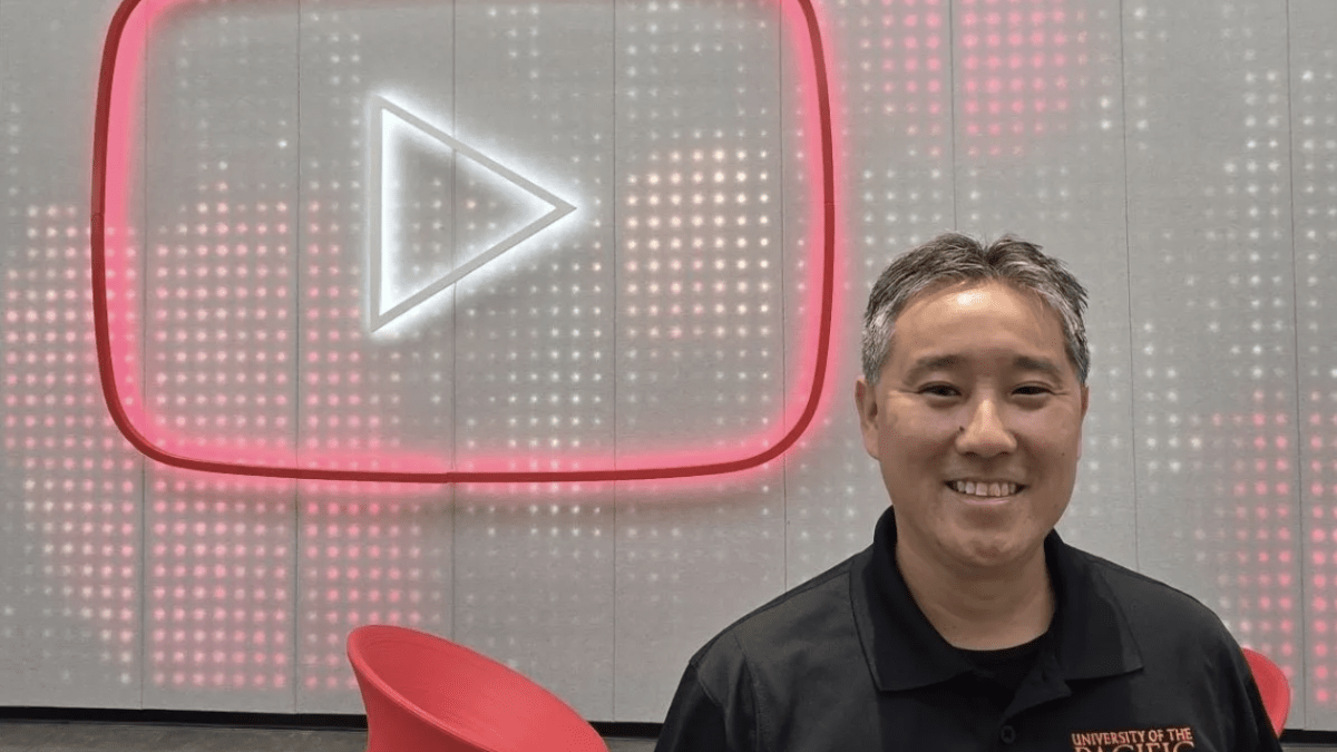 A man wearing a black polo shirt sits in front of the YouTube logo