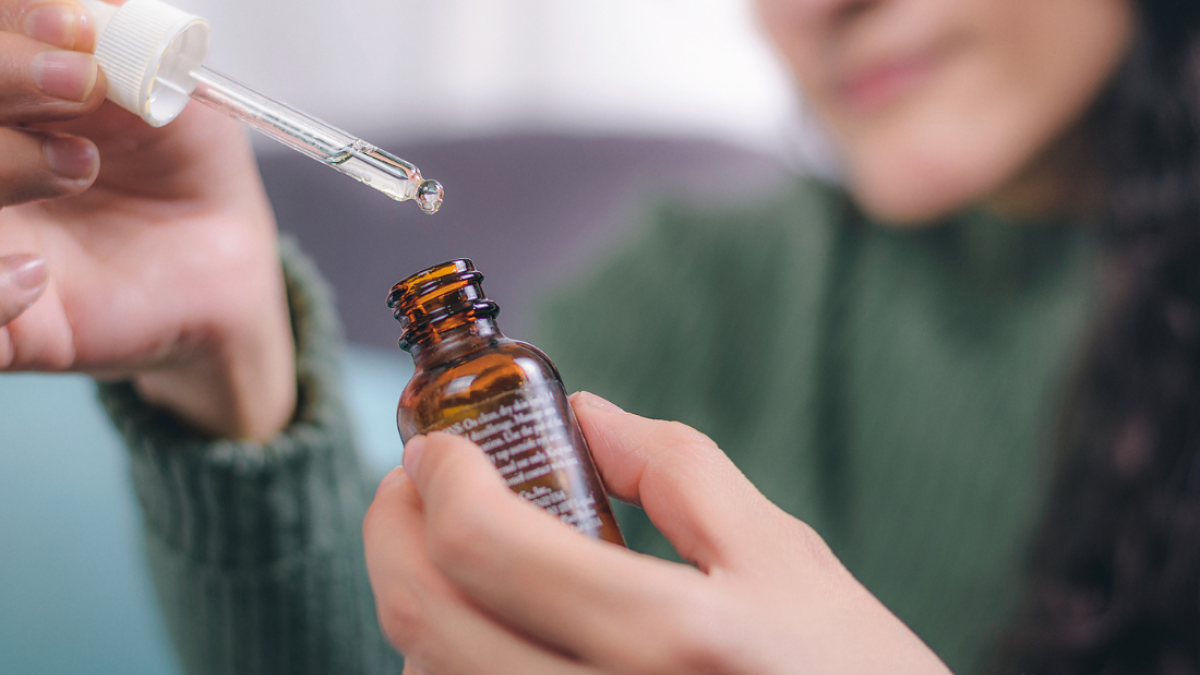 a woman holds a medicine dropper
