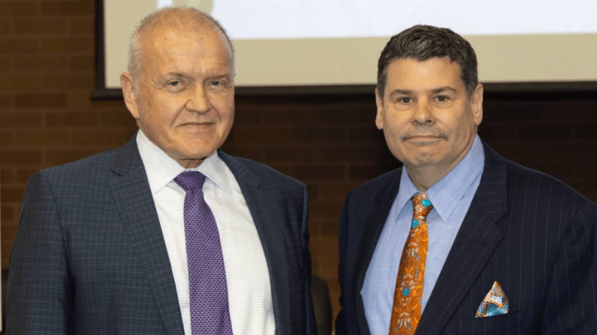 Mark Drobny and Michael T. Colatrella Jr. smile in front of a presentation