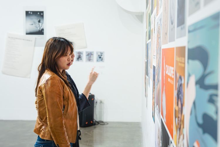 Achish Enriquez ’26, a media arts and production major, views her work alongside her peer at Reynolds Gallery.