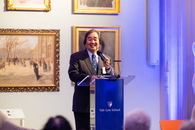 A portrait of a man speaking at a podium