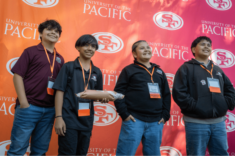 Students smiling in front of 49ers and Pacific branded backdrop