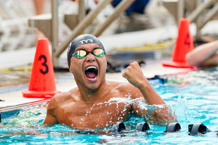 A swimmer in googles pumps his fist in victory in the pool