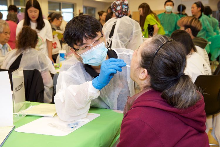 dental student examining the mouth of a senior female patient