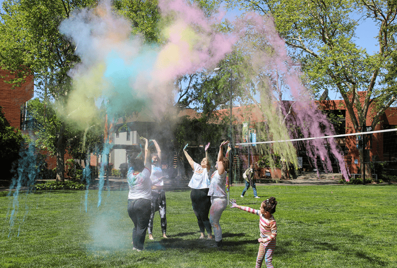 Individuals participating in outdoor event with colored powdered for Holi. 