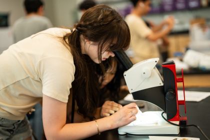 A student looks into a microscope at the Pacific Summer High School Institute.