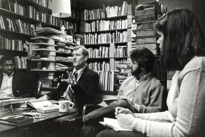Larry Meredith sits at a table with students in a black and white image