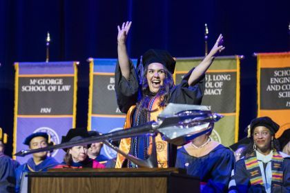 A student cheers as she walks across the stage at commencement.