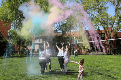Individuals participating in outdoor event with colored powdered for Holi. 