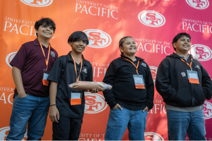 Students smiling in front of 49ers and Pacific branded backdrop
