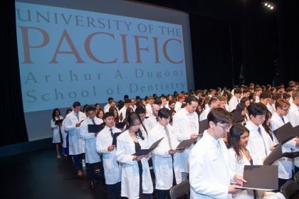 Students stand at their white coat ceremony
