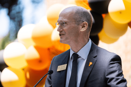 James Walsh stands in front of balloons as he gives a speech.