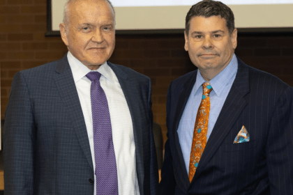 Mark Drobny and Michael T. Colatrella Jr. smile in front of a presentation.