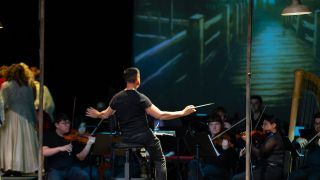 A conductor with an orchestra of a musical performance