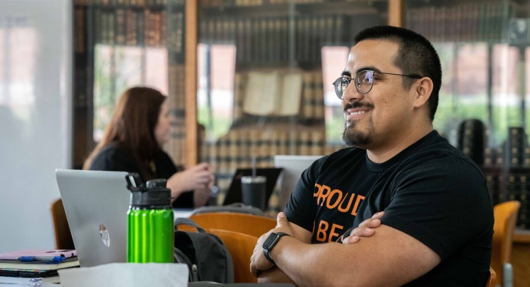 a student at a table with old books in the background