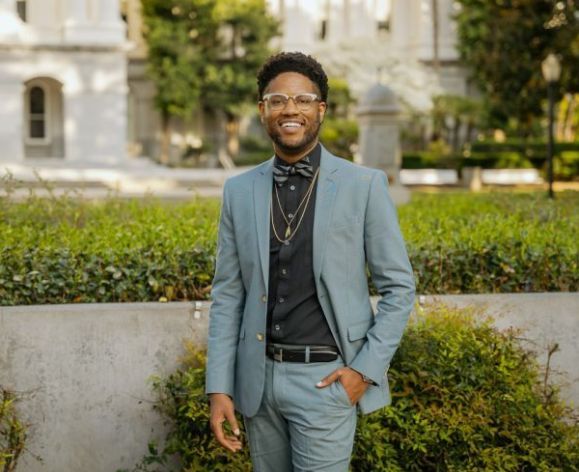 Man in blue suit smiles for a photo