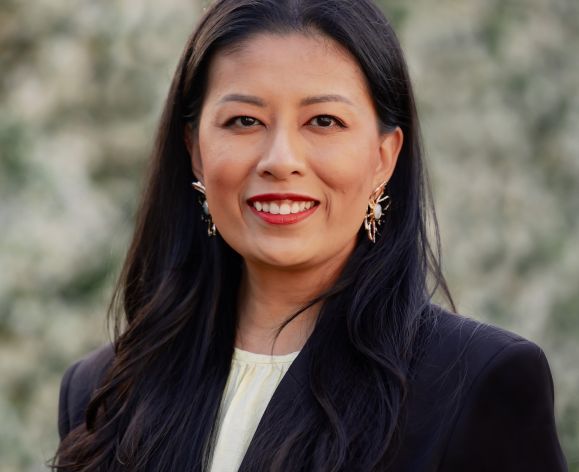 woman in black suits smiles for head shot
