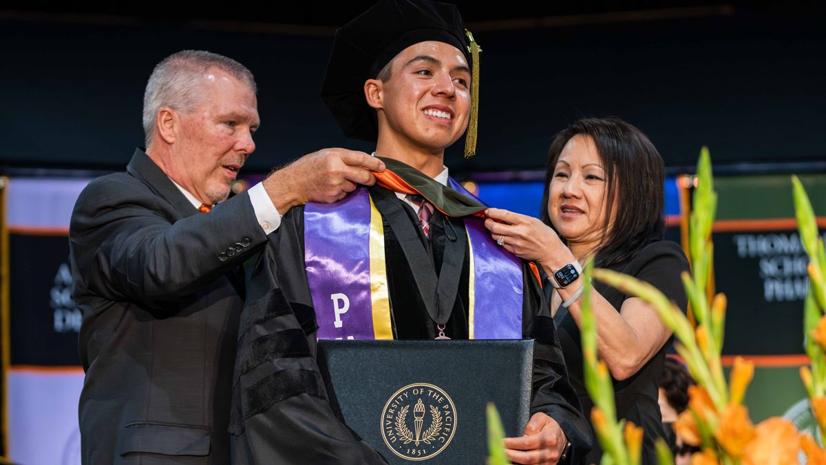 PharmD graduate is hooded by his legacy alumni parents at Commencement