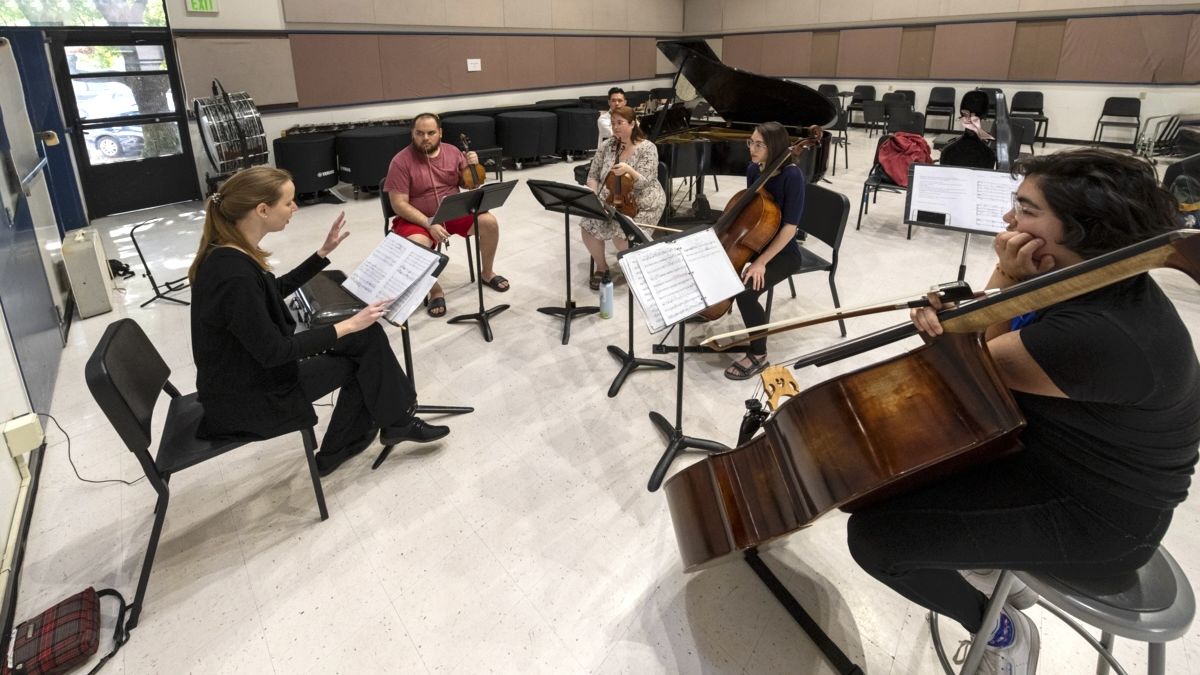 a music professor conducts several students playing different instruments