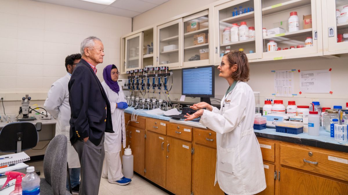 a professor talks to two adults in a lab